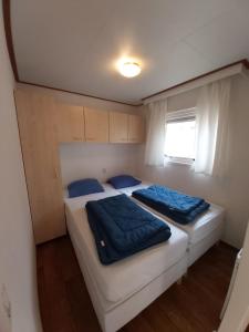 twee bedden in een kleine kamer met een raam bij Chalet type F in Voorthuizen