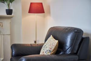 a brown leather chair with a pillow in a living room at Cosy and convenient cottage in Bishop Auckland