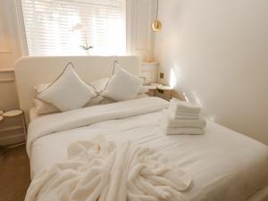 uma cama branca com lençóis brancos e almofadas em Arbour House Farm Bungalow em Durham