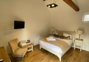 a bedroom with a bed and a chair at Great Blunts Stables in Billericay