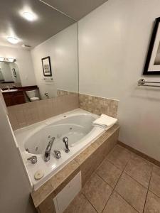 ein Badezimmer mit einer großen Badewanne und einem Spiegel in der Unterkunft Peaceful Golf Spa in Collingwood
