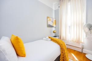 um quarto com uma cama branca com almofadas amarelas e uma janela em 6 Bedroom House by AV Stays Acton Sleeps 11 Free Parking em Londres