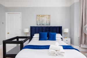um quarto com uma cama azul e branca com almofadas azuis em 6 Bedroom House by AV Stays Acton Sleeps 11 Free Parking em Londres