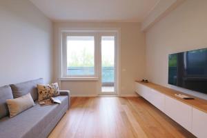 een woonkamer met een bank en een grote televisie bij Contempora Apartments - Elvezia 8 - E43 in Milaan