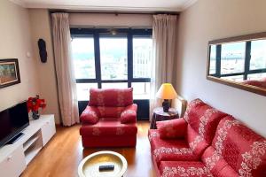 sala de estar con sofá rojo y silla en Apartamento 3 Dormitorios Playa Foz, en Foz