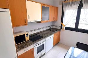 una pequeña cocina con armarios de madera y fregadero en Apartamento 3 Dormitorios Playa Foz, en Foz