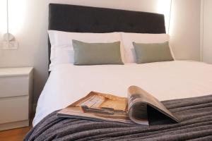 een tijdschrift en een schoen bovenop een bed bij Contempora Apartments - Elvezia 8 - E43 in Milaan