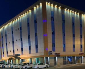 een groot gebouw met auto's geparkeerd voor het bij فندق نجمة سماء ينبع البحر in Yanbu