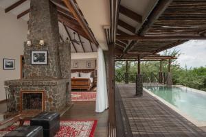 a room with a fireplace and a swimming pool at Ngorongoro Oldeani Mountain Lodge in Oldeani