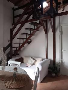 a living room with a white couch and wooden stairs at La soffitta di Megan in Cesano