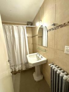 a bathroom with a sink and a mirror and a radiator at Hosteria El Ñire in San Carlos de Bariloche