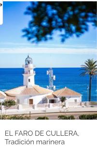 a building with a lighthouse in front of the ocean at 1era linea de playa Cullera Villa Sales in Cullera
