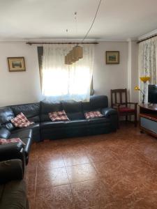 a living room with a black couch and a window at 1era linea de playa Cullera Villa Sales in Cullera