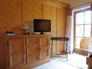 a television on a wooden cabinet in a room with a window at Landhaus Am Arzbach in Bad Tölz