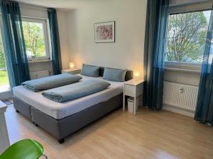 een slaapkamer met een bed met blauwe kussens en 2 ramen bij Ferienwohnung Gary mit zwei Terrassen und Garten in Garmisch-Partenkirchen