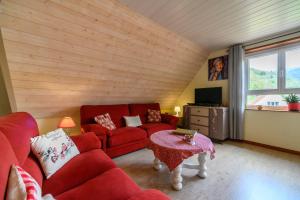 salon z czerwoną kanapą i stołem w obiekcie Gîte en montagne vosges alsaciennes w mieście Fréland