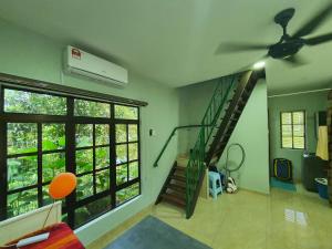a living room with a staircase and a ceiling fan at Teratak D Tuntung in Kampong Mesjid