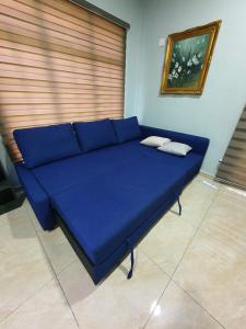 a blue couch in a room with a window at Teratak D Tuntung in Kampong Mesjid