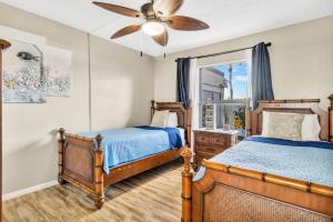 a bedroom with two beds and a ceiling fan at Cape Winds Resort in Cape Canaveral