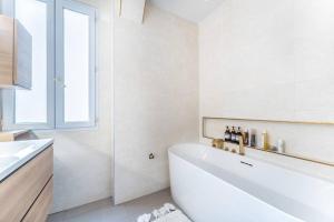 een witte badkamer met een bad en een raam bij Appartement cosy à 5min de Paris in Saint-Mandé