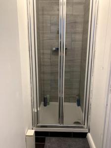 um chuveiro com uma porta de vidro na casa de banho em Warren Street Guest House em Londres