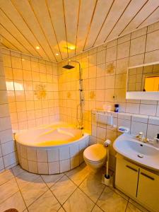 a bathroom with a tub and a toilet and a sink at B&R Ferienhaus In der Nähe des Flughafens in Nürnberg