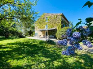 una casa de piedra con un patio con flores púrpuras en Le Clos Pastel en Virac