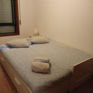 a bed with two pillows and a towel on it at Casa Familiar Porto in Porto