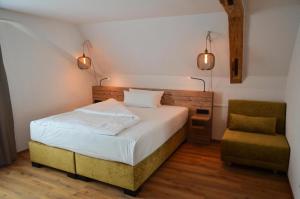 a bedroom with a bed and a chair and lights at Gasthof zum Ritter - a cozy historical Landmark in Ulm