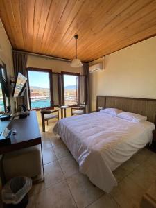 a bedroom with a bed and a desk and windows at Helena Hotel in Chania