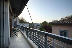 einen Balkon mit einem grünen Stuhl auf einem Gebäude in der Unterkunft Modern 2BD apartment next to Acropolis in Athen