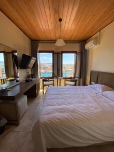 a bedroom with a bed and a desk with a view at Helena Hotel in Chania