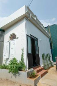 uma pequena casa branca com plantas em frente em LING LING'S VILLA em Mộc Châu
