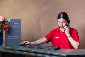 Eine Frau, die auf einem Handy neben einem Computer redet. in der Unterkunft Ibis Oujda in Oujda