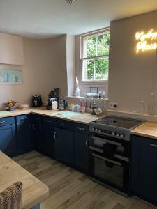 a kitchen with blue cabinets and a black stove at Stunning 2-bedroomed Cottage in Cockermouth