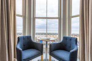 dwa krzesła i stół w pokoju z oknami w obiekcie The Majestic Hotel w mieście Eastbourne