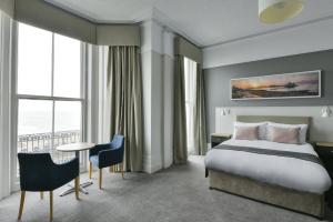 a hotel room with a bed and a table and chairs at The Majestic Hotel in Eastbourne