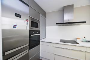 uma cozinha com armários brancos e um frigorífico de aço inoxidável em Rey apartment em Vilassar de Mar