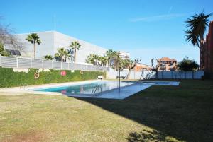 uma piscina num quintal com um edifício e palmeiras em Rey apartment em Vilassar de Mar