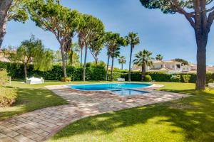 a swimming pool in a yard with palm trees at Villa Oliveiras de Vilamoura by The Portuguese Butler in Quarteira