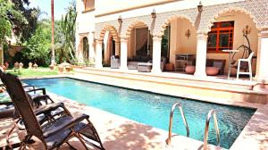 - une piscine avec 2 chaises et une maison dans l'établissement Barthélemy Guest House, à Marrakech