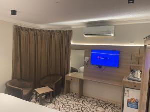 Habitación de hotel con escritorio y TV en la pared en Dvina Hotel en Tabuk