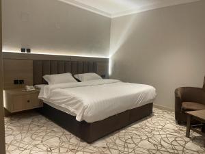 Dvina Hotel في تبوك: غرفة نوم بسرير كبير وكرسي