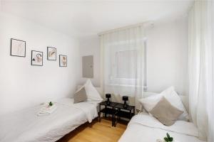 M B Homes في Balzholz: سريرين في غرفة بجدران بيضاء
