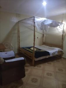 - une chambre avec un lit à baldaquin et un canapé dans l'établissement Merricks Guest House, à Litein