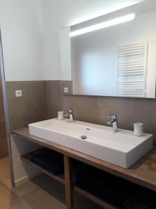 een badkamer met een witte wastafel en een spiegel bij Maison climatisée avec piscine privée, 6 personnes in Aiguèze