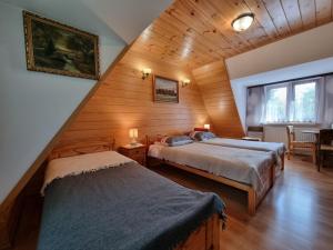 a attic bedroom with two beds in a room at Domek Pod Klonem Agroturystyka in Białowieża