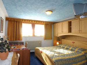 a hotel room with a bed and a desk and a window at Hotel Pordoi - Fam Furgler in Arabba