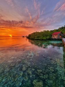 a sunset over a body of water with a house at Raja Ampat Blue Sea in Besir