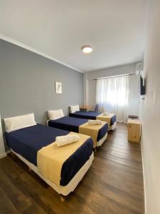 a room with three beds and a television in it at Hotel Chacabuco in Buenos Aires